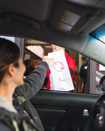 Woman picking up drive-through takeout in car